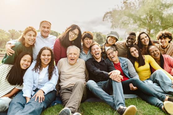 Image of many different people of different ages, cultures, and genders sitting together and smiling.
