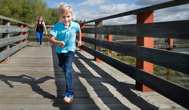 Photo of young boy running down the boardwalk on Telford Lake