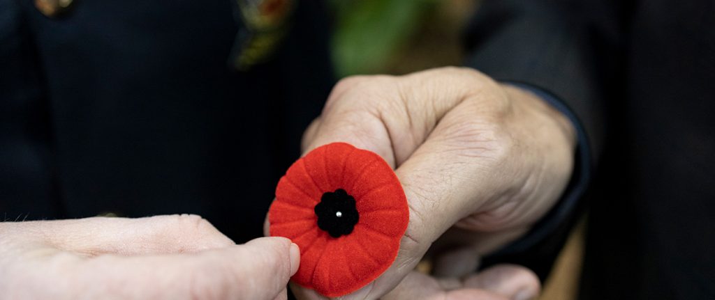 Old veterans holding onto a poppy during Remembrance Day ceremony in Leduc.