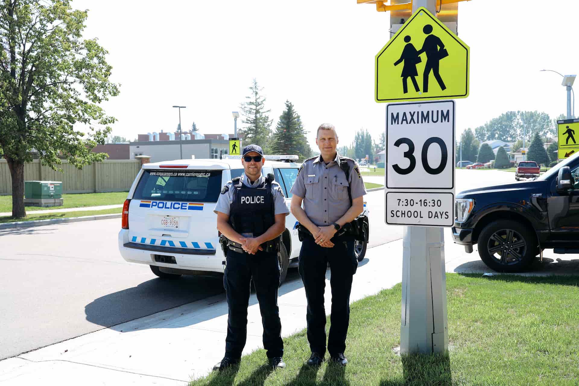 Two Leduc police officers posing for a photo and smiling in front of a local street.