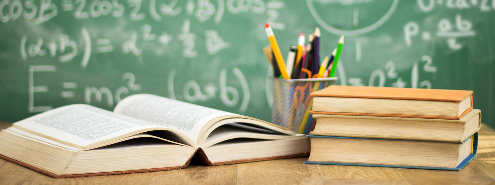 http://Open%20book,%20stacked%20books,%20and%20a%20container%20of%20pencils%20in%20front%20of%20a%20chalkboard%20with%20mathematical%20equations.