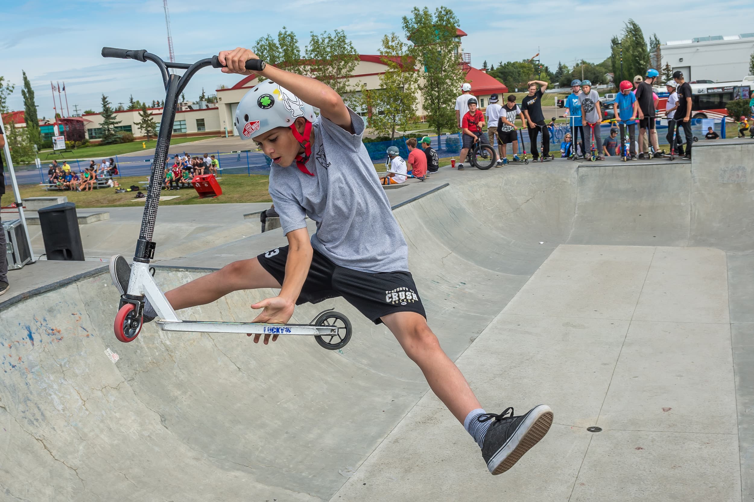 A person performing tricks with a scooter on a skate ramp.