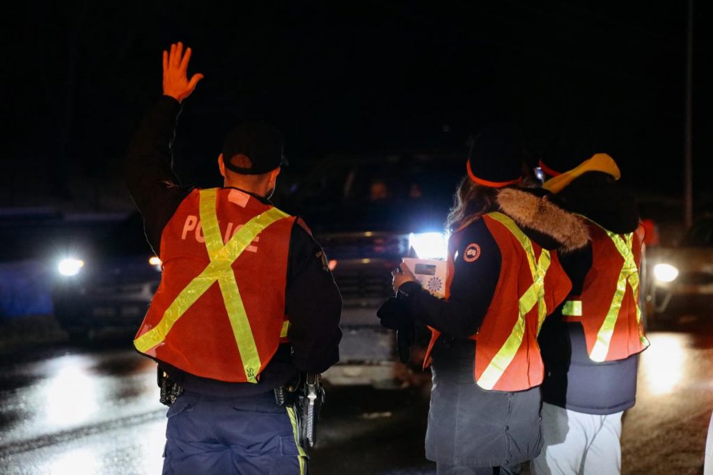 City of Leduc Police officers waving to cars at the 2024 Candy Cane Checkstop