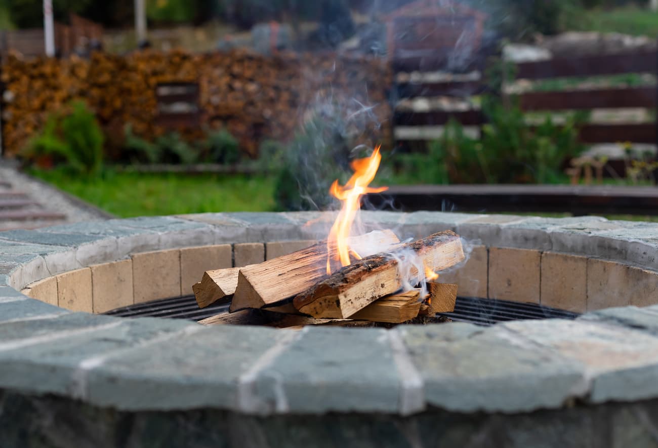 image of brick fire pit with split wood and open fire burning.