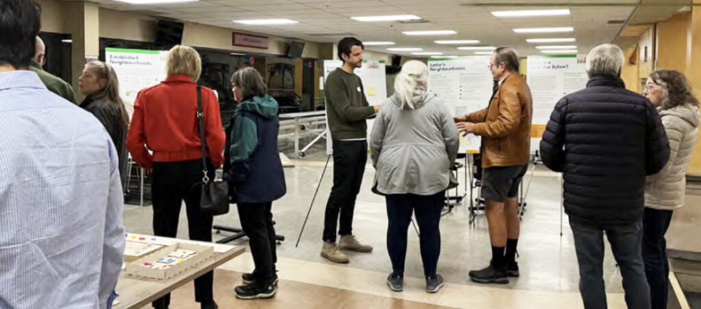 A group of people gathered in the LRC at an information session, viewing display boards and speaking with staff about the Land Use Bylaw