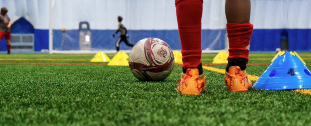 Indoor soccer training on a turf field, representing recreation amenities at the West Campus Recreation Project.