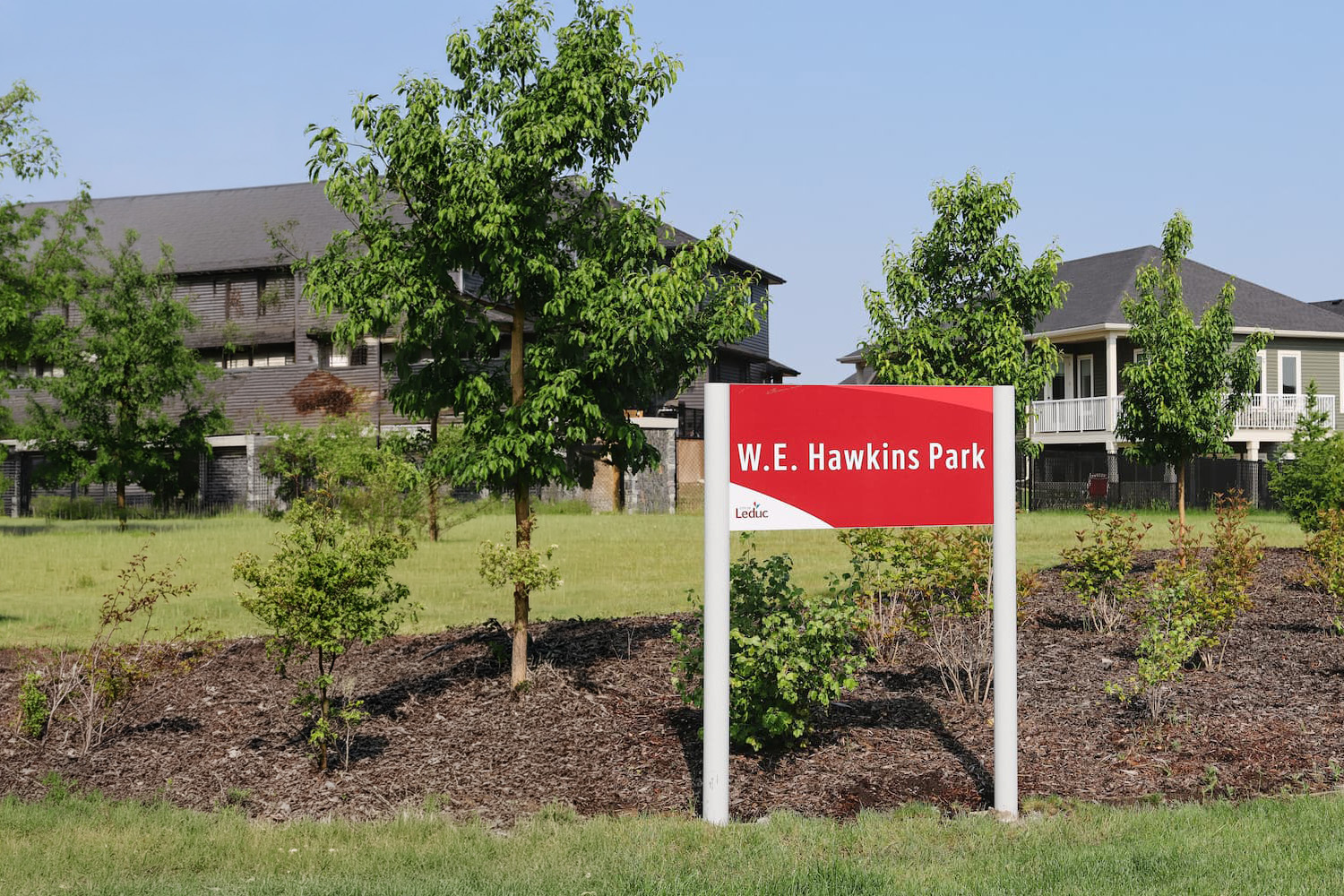 http://New%20W.E.%20Hawkins%20Park%20sign%20installed%20in%20the%20Woodbend%20neighbourhood,%20with%20landscaped%20green%20space%20and%20nearby%20homes%20in%20the%20background.
