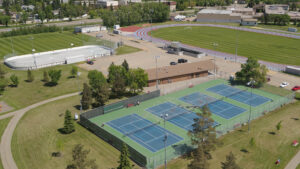 Aerial view of Kinsmen Park in Leduc, featuring tennis courts, a running track, sports field and outdoor rink.